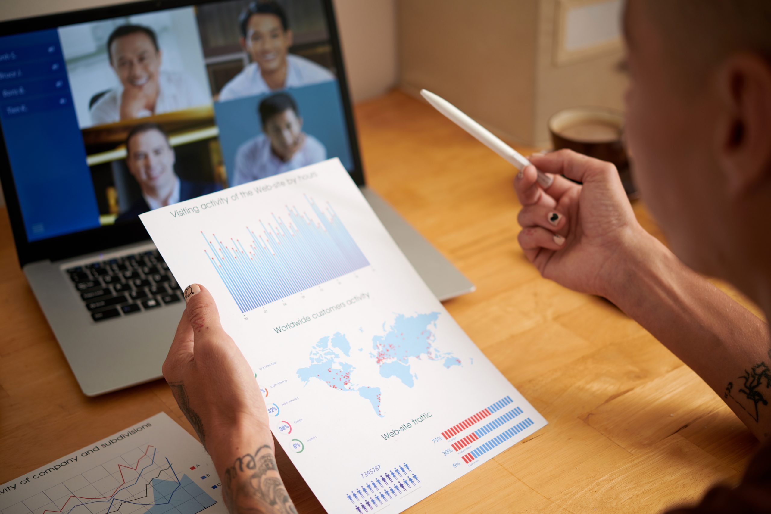 Marketing department manager holding report with charts showing customers activity when talking to colleagues in online meeting